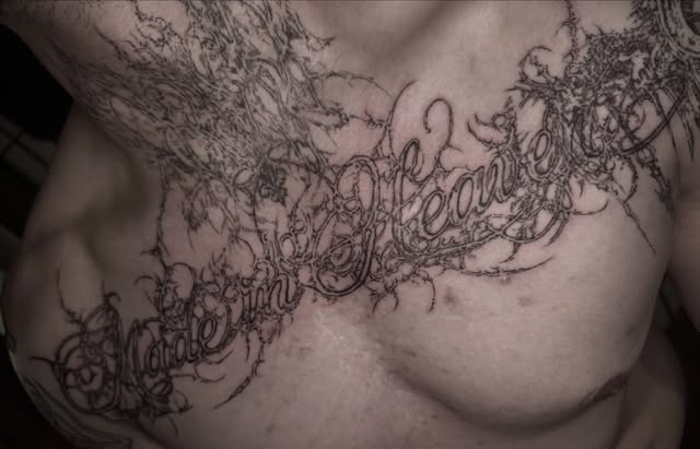 ornamental script tattoo across the chest