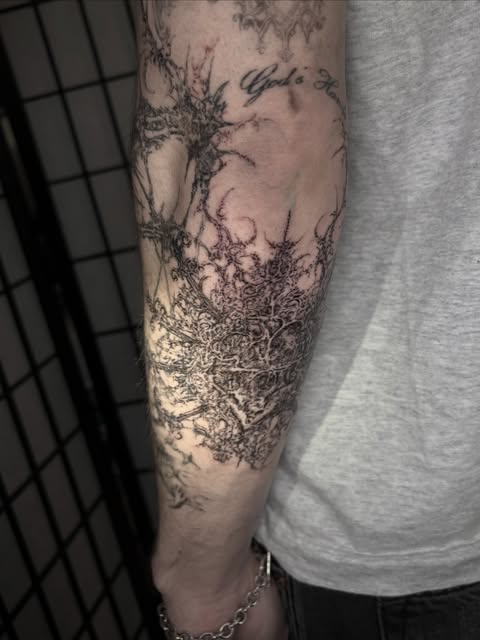 dense illustrative black and gray forearm tattoo