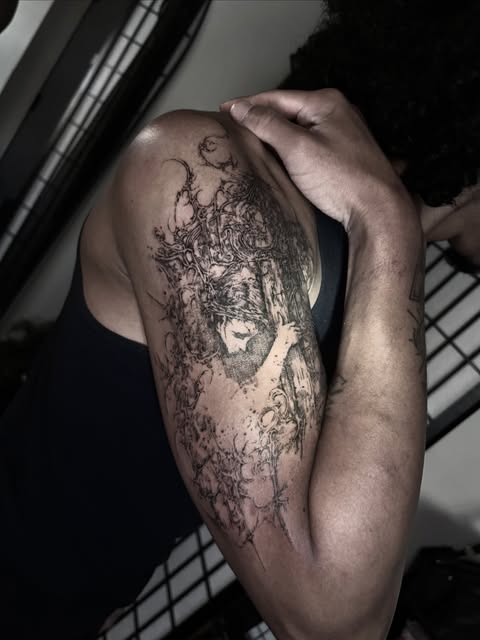 figurative black and gray upper-arm tattoo